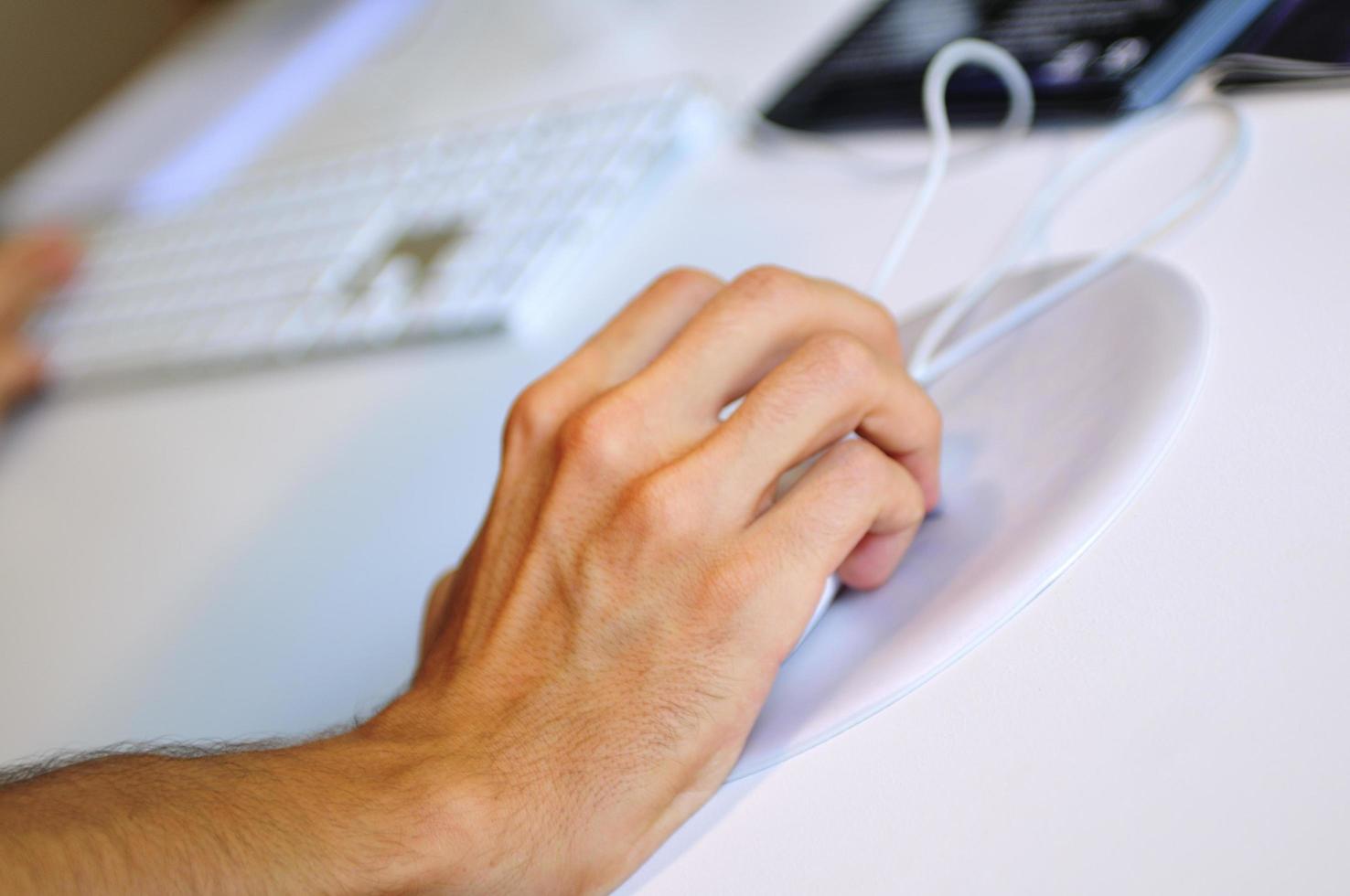 lose-up of male hand on mouse while working on laptop photo