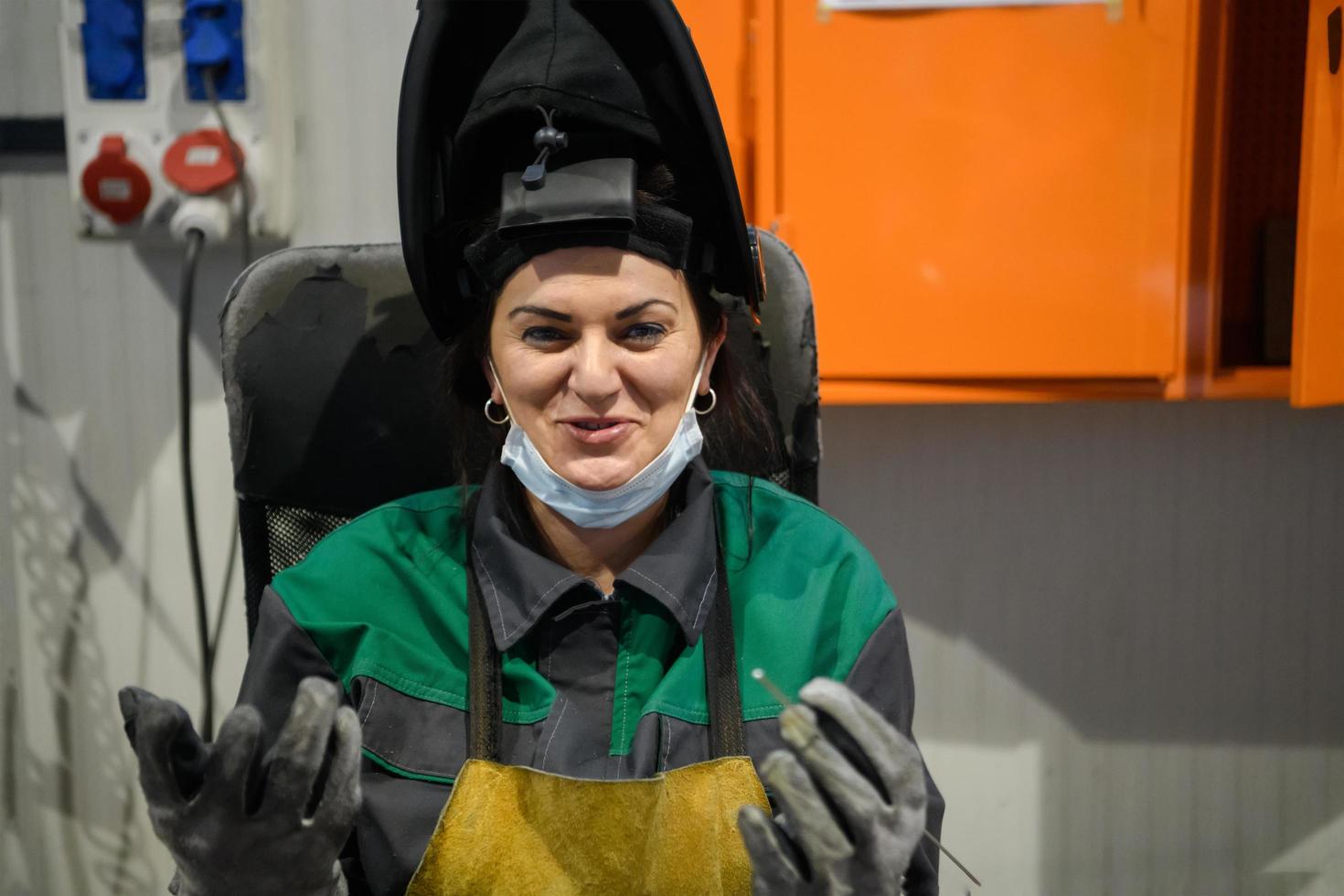 A woman employed in a modern factory for the production and processing of metals in a work uniform welds metal materials photo