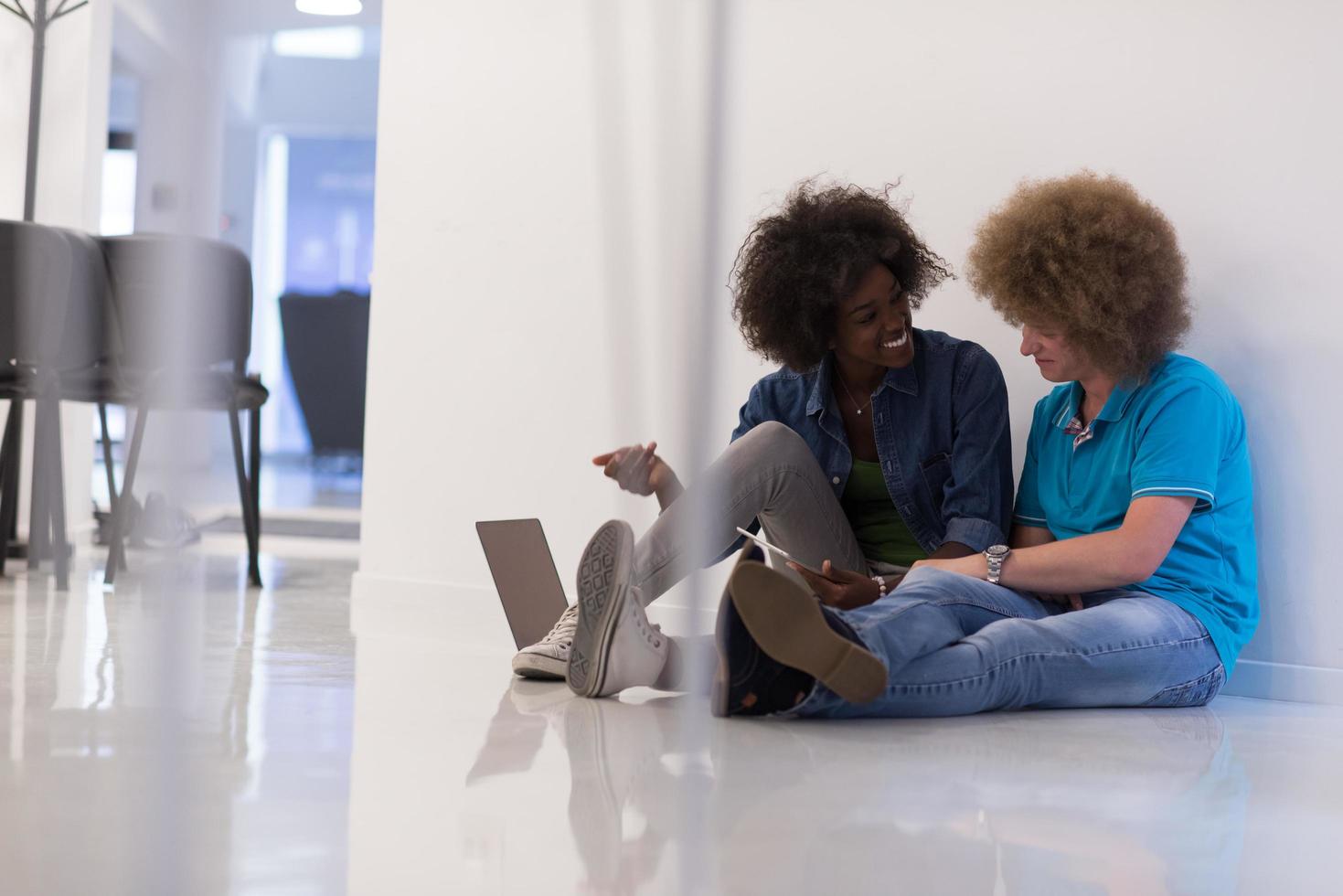 multiethnic couple sitting on the floor with a laptop and tablet photo