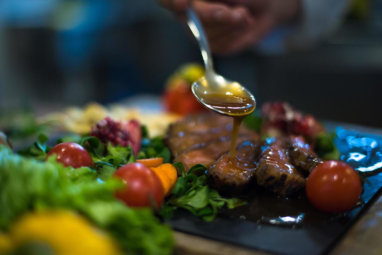 Chef hand finishing steak meat plate photo