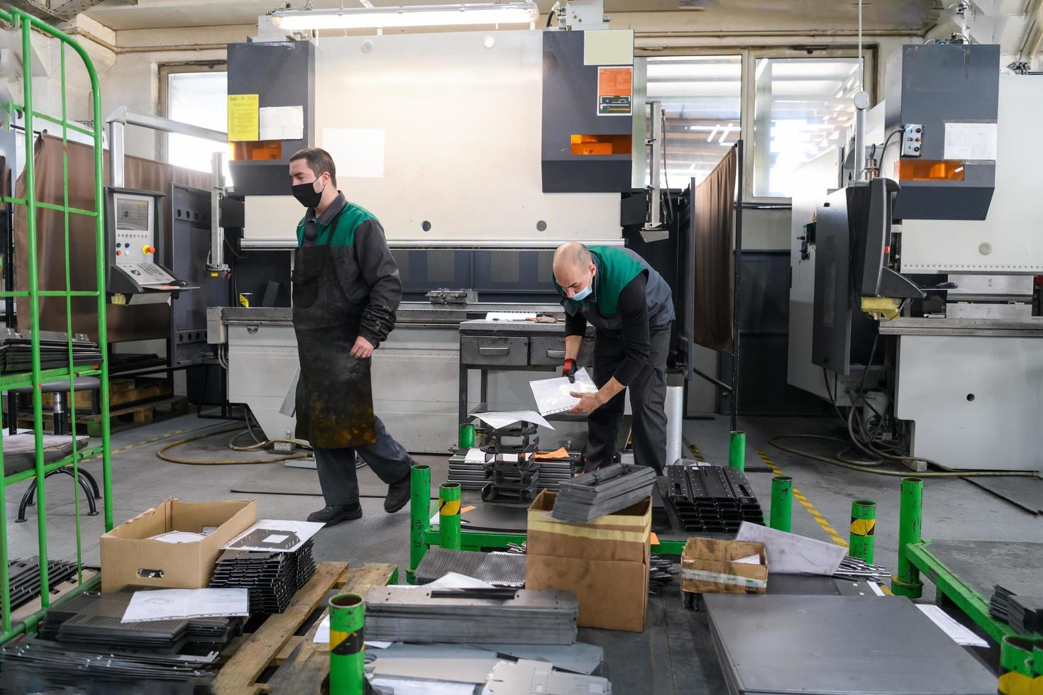 Turkey, 2022 - two workers wearing a protective mask due to a coronavirus pandemic, working in a modern factory and preparing a program and materials for a cnc machine photo