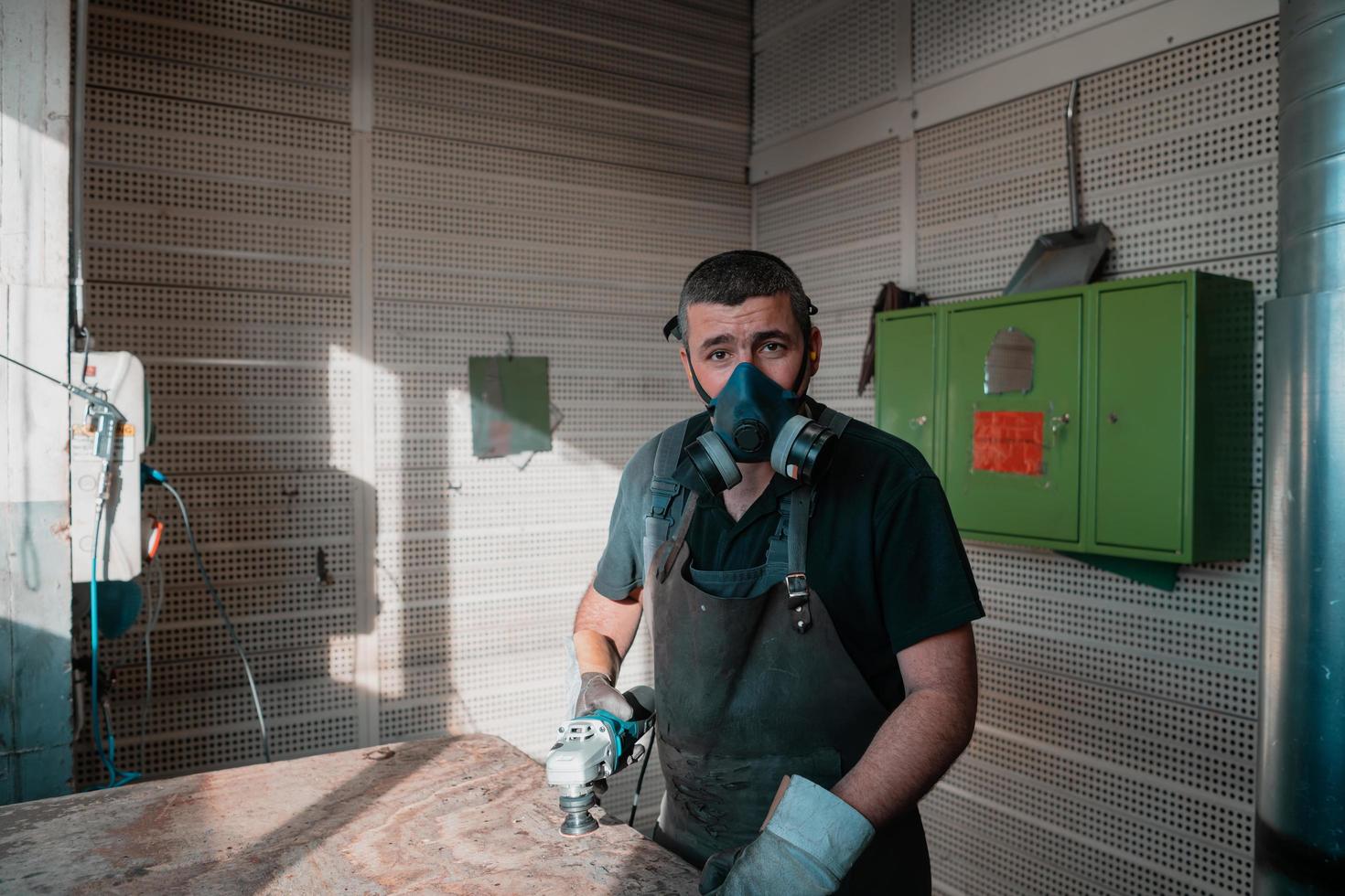 Heavy Industry Engineering Factory Interior with Industrial Worker Using Angle Grinder and Cutting a Metal Tube. Contractor in Safety Uniform and Hard Hat Manufacturing Metal Structures. photo