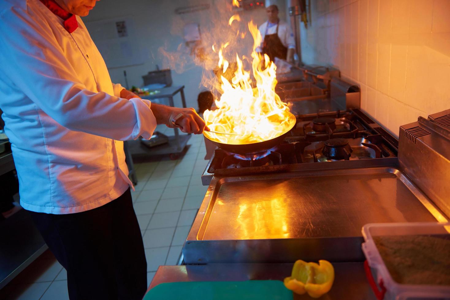 chef en la cocina del hotel prepara comida con fuego foto