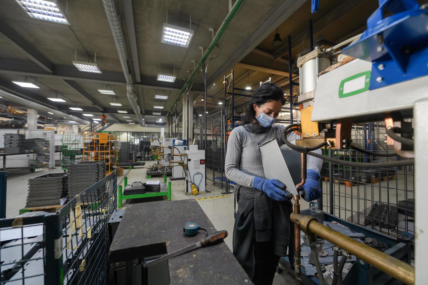 Turkey, 2022 - woman working in the metal industry in the production of new machines wears a face mask during work due to the coronavirus pandemic photo