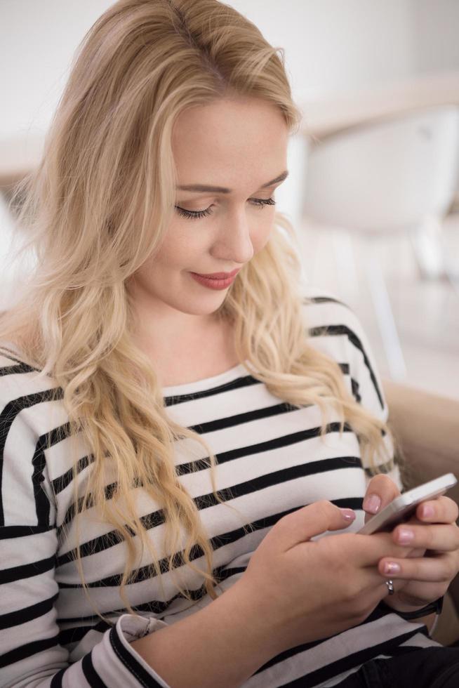 woman sitting on sofa with mobile phone photo