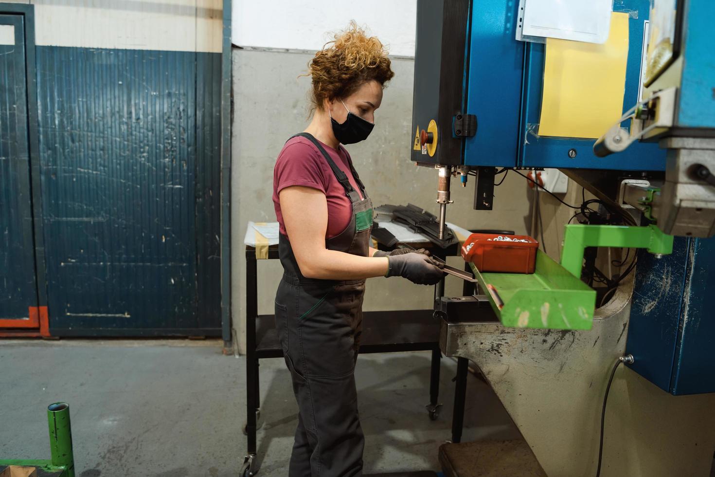 woman wearing mask due to coronavirus pandemic while working in modern metal industry and using drill photo