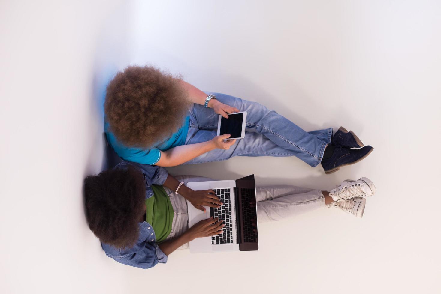 multiethnic couple sitting on the floor with a laptop and tablet top view photo