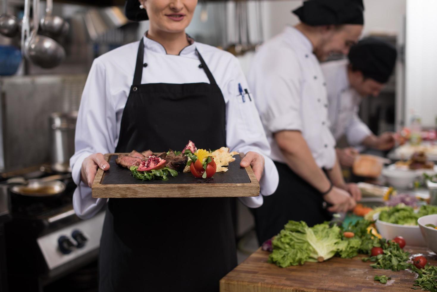 female Chef holding beef steak plate photo