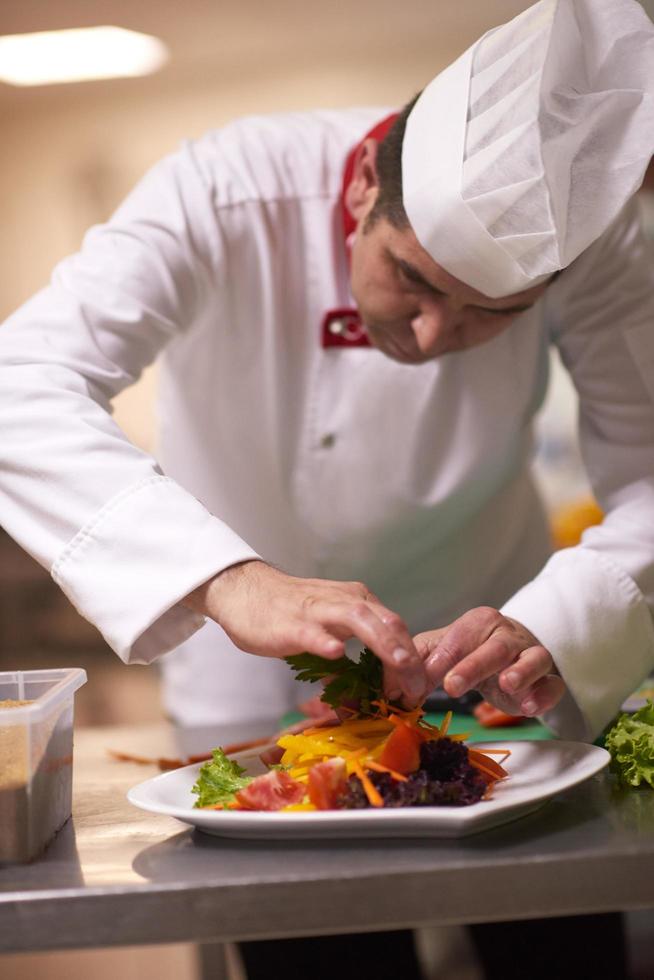 chef in hotel kitchen preparing and decorating food photo