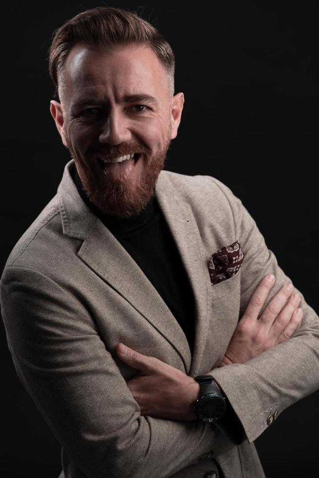 Portrait of a stylish elegant senior businessman with a beard and casual business clothes in photo studio isolated on dark background gesturing with hands