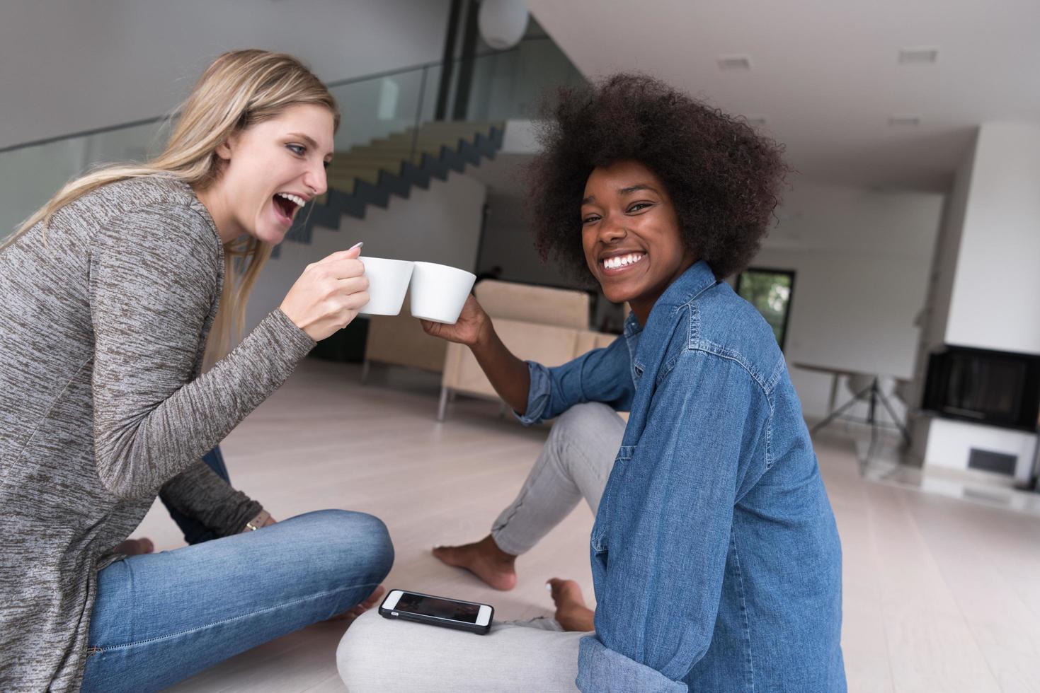 young multiethnic women sit on the floor and drinking coffee photo