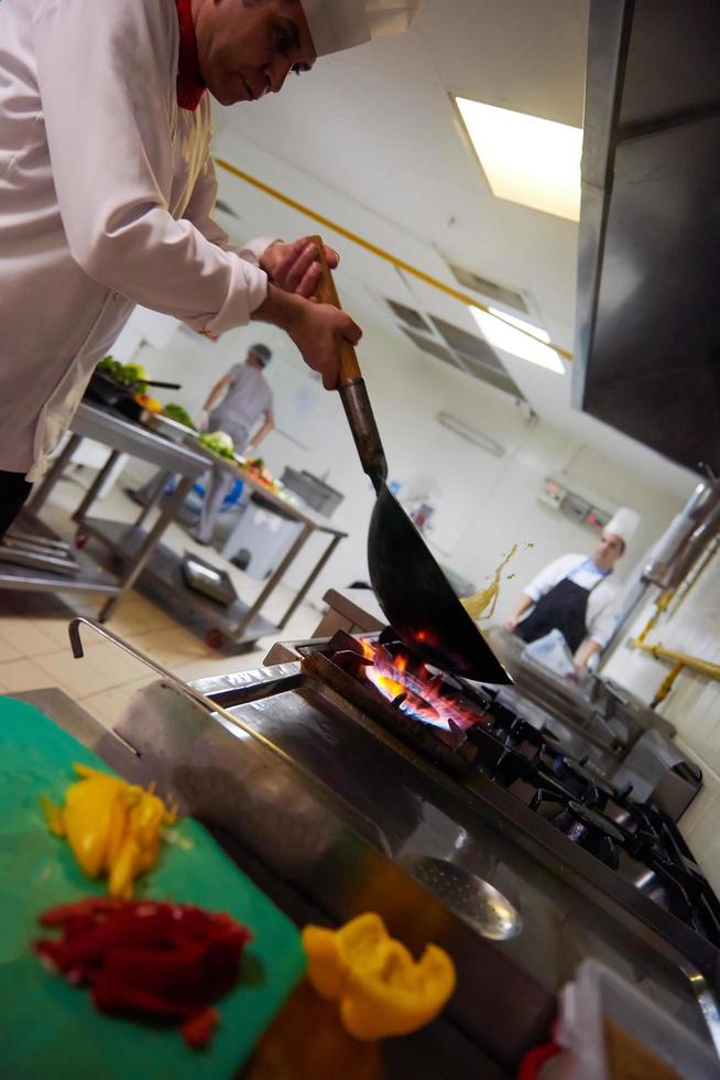 chef in hotel kitchen prepare food with fire photo