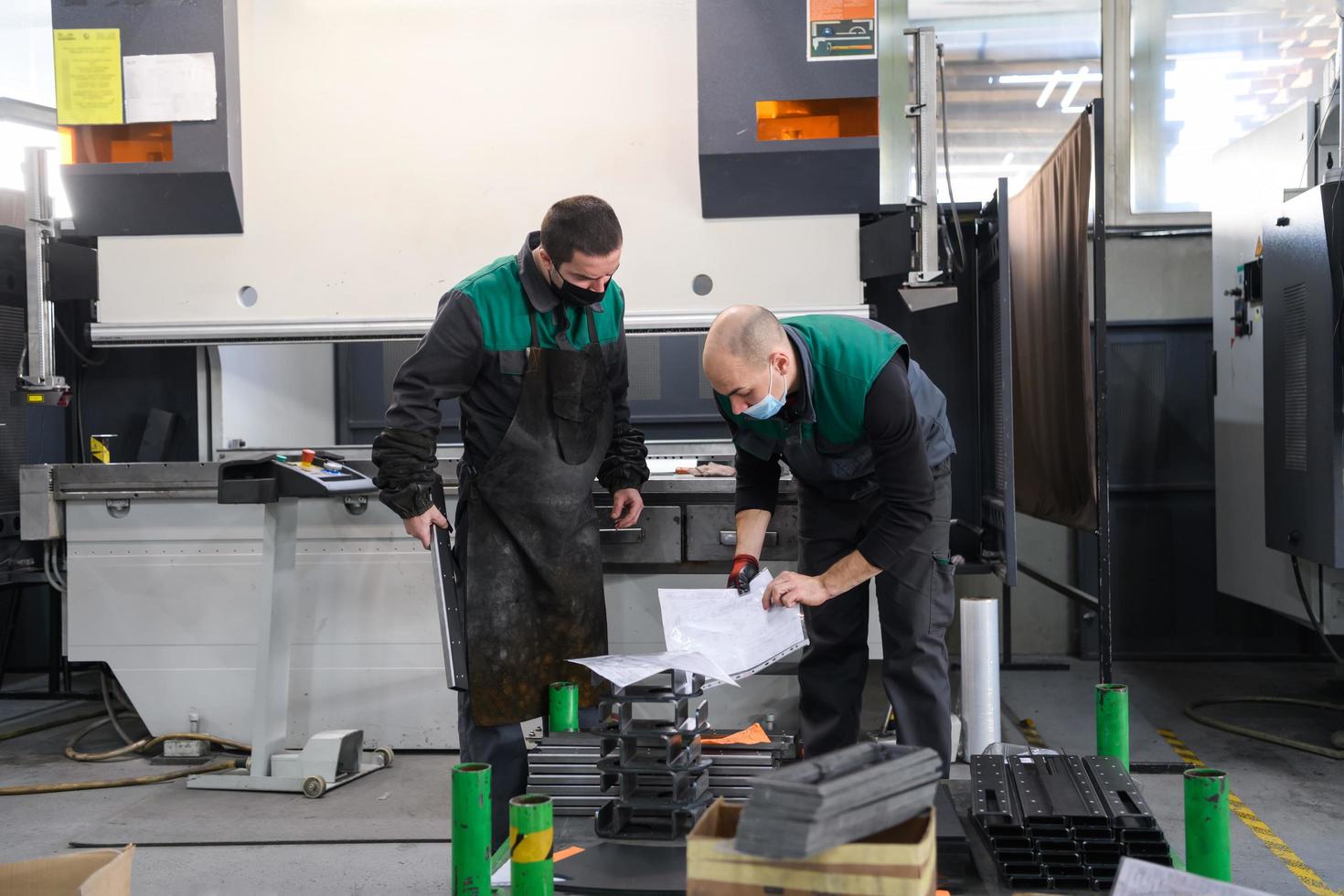 two workers wearing a protective mask due to a coronavirus pandemic, working in a modern factory and preparing a program and material for a cnc machine photo