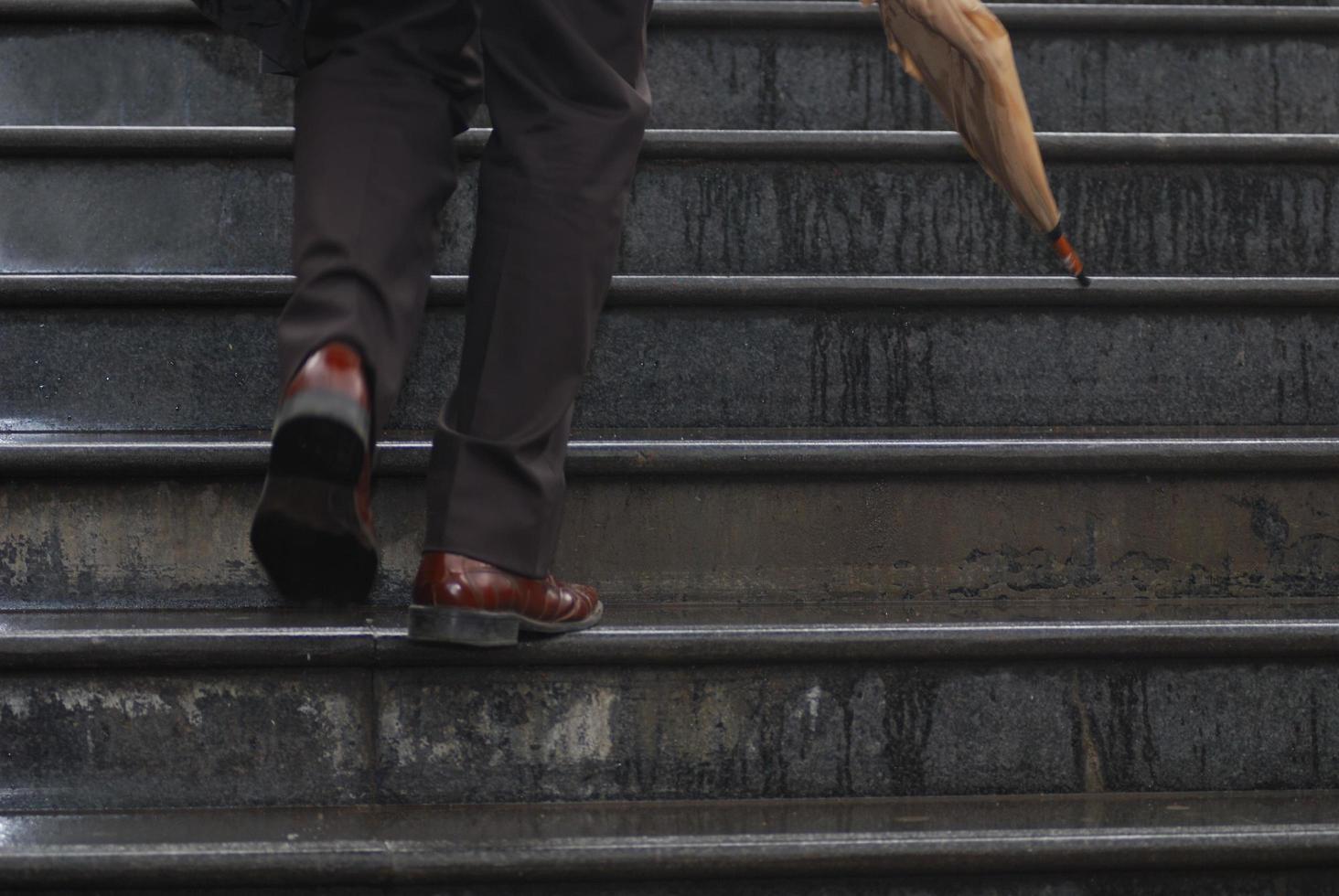 ejecutivo de negocios subiendo escaleras con paraguas en la mano foto