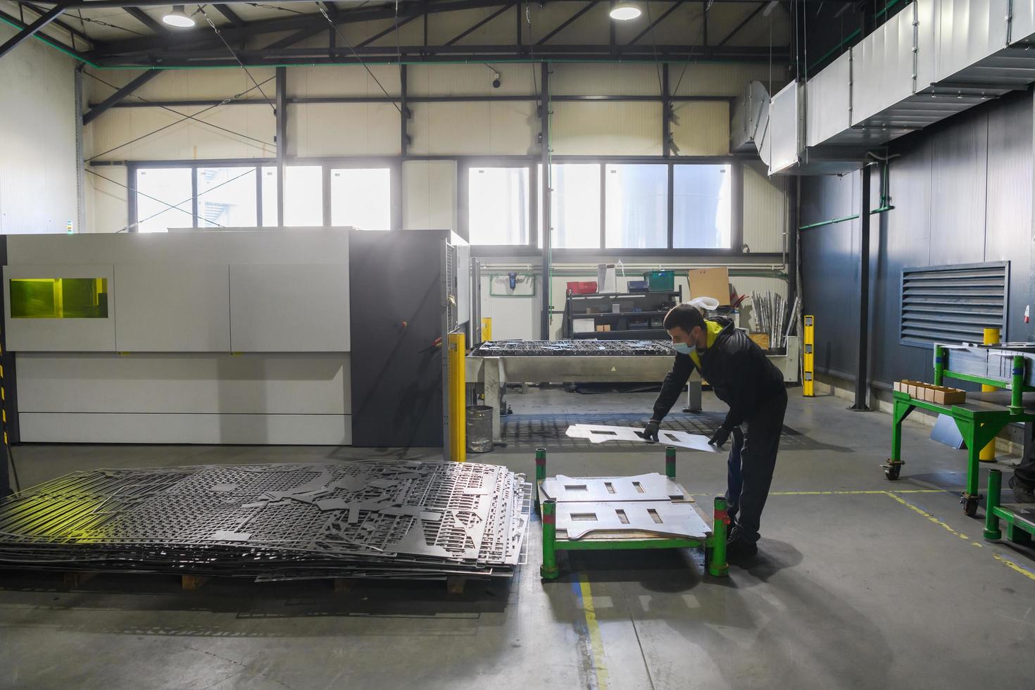 Turkey, 2022 - a worker working in a modern industry prepares material for processing on a cnc machine, wears a protective mask on his face due to a coronary virus pandemic photo