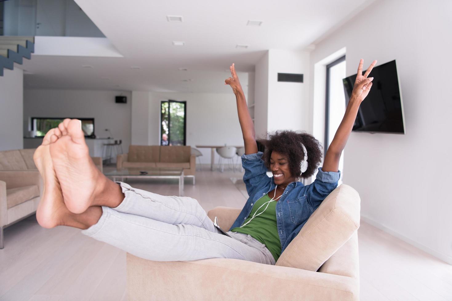 mujer afroamericana en casa en silla con tableta y auriculares foto