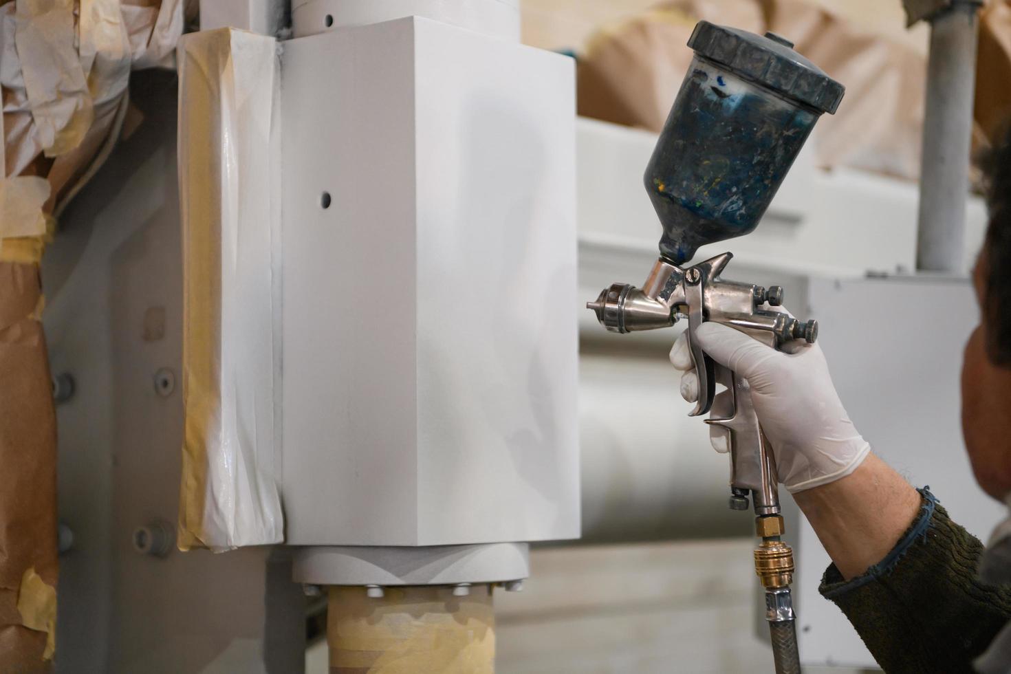 A worker painting to mechanical part with airless spray photo