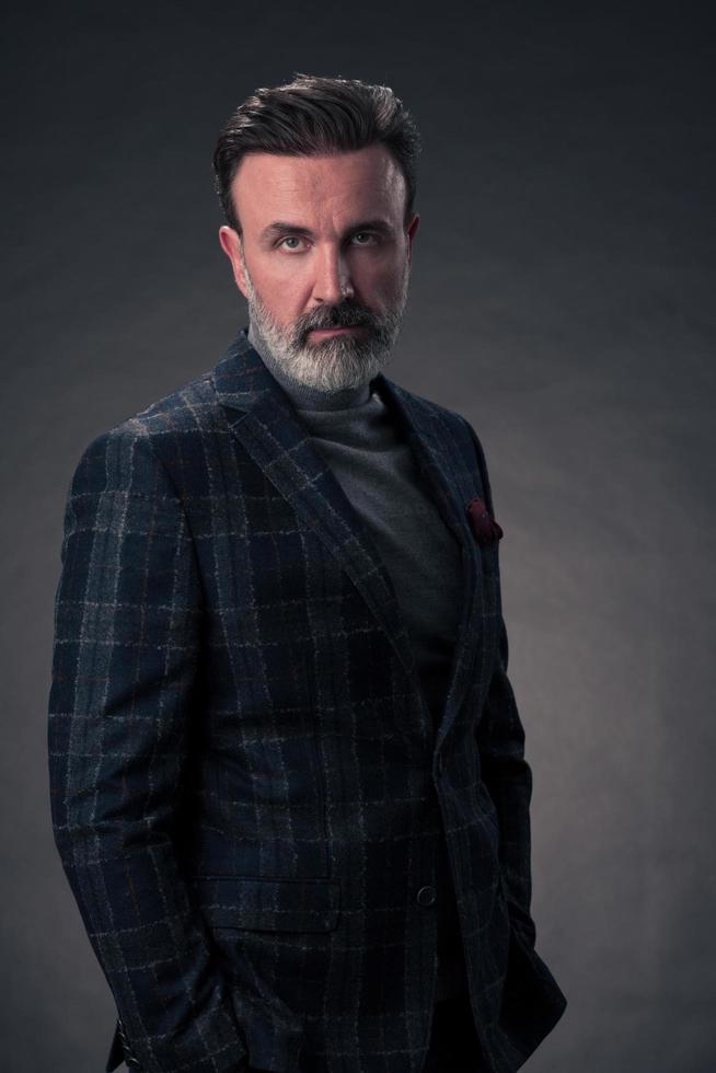 retrato de un elegante hombre de negocios de alto nivel con barba y ropa informal de negocios en un estudio fotográfico aislado en un fondo oscuro gesticulando con las manos foto