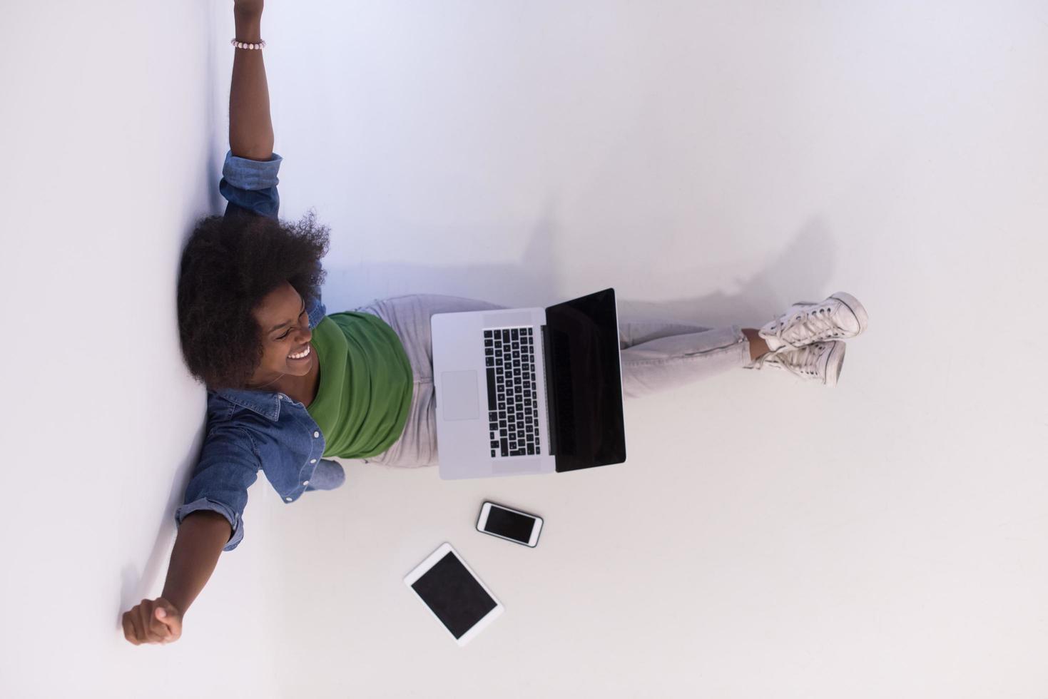 african american woman sitting on floor with laptop top view photo