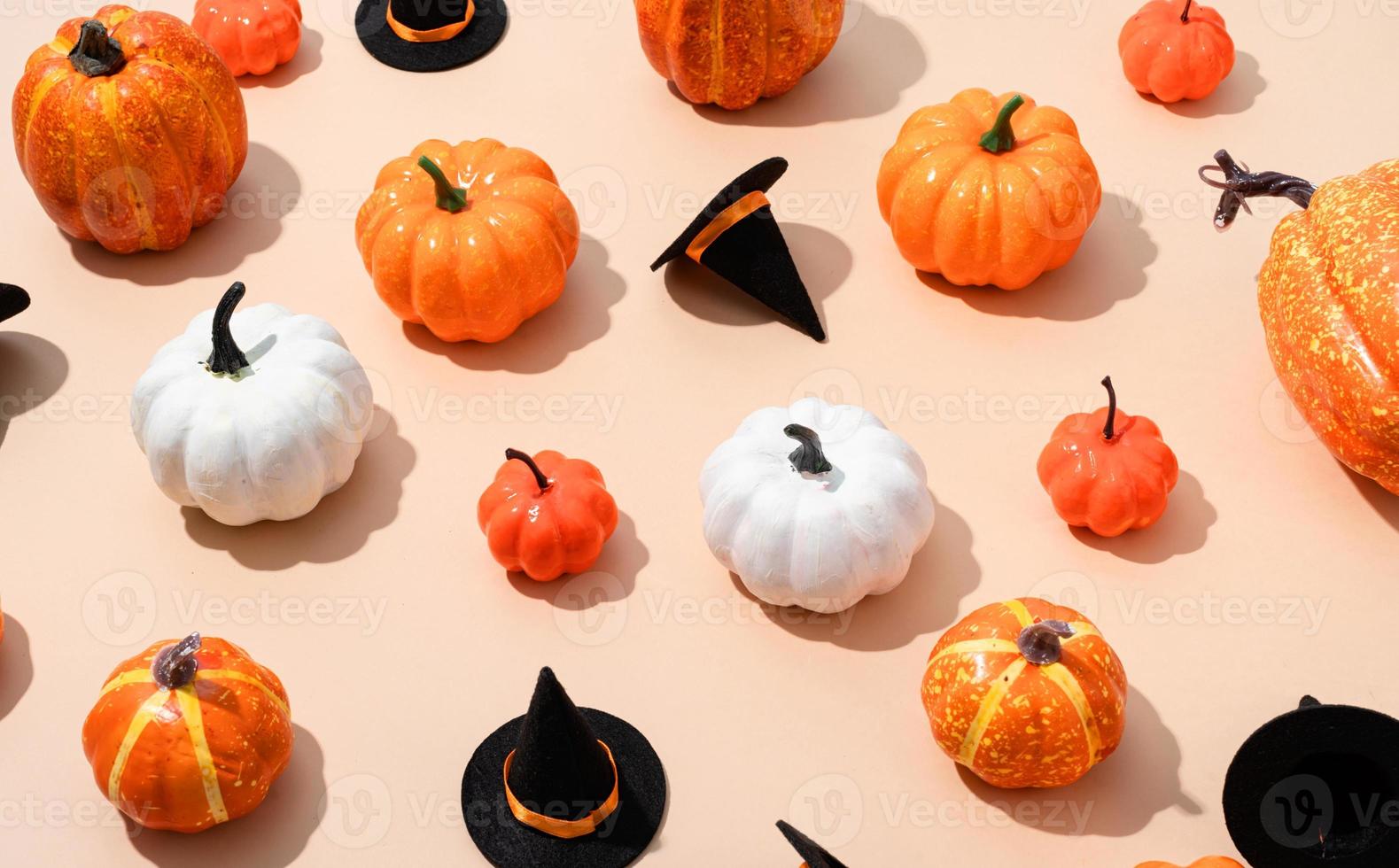 pattern of colorful artificial pumpkins and halloween hats on orange background photo