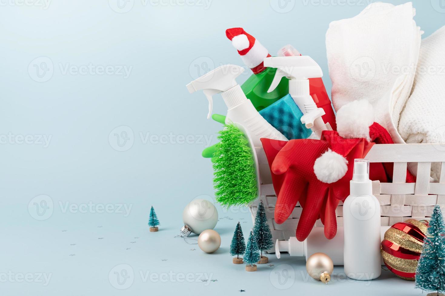 herramientas de limpieza y adornos navideños en una cesta de ropa blanca sobre fondo azul con espacio para copiar foto