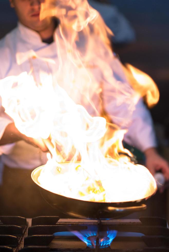 chef haciendo flambeado en la comida foto