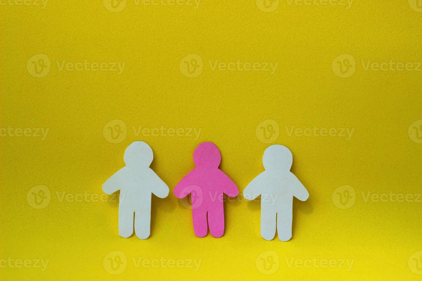 Paper cut pink human between two white paper people shapes. Three figures. Social interaction concept. Team work. Diversity. photo