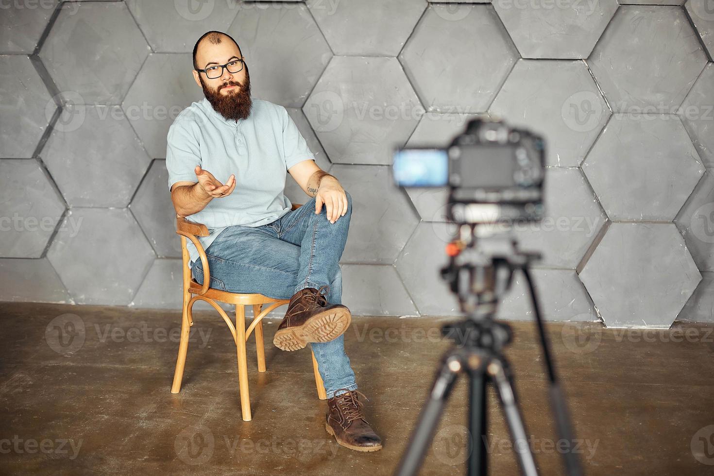 content creation for social media. bearded man shooting video of himself using camera on tripod. modern technology and blogging freelance work concept. photo