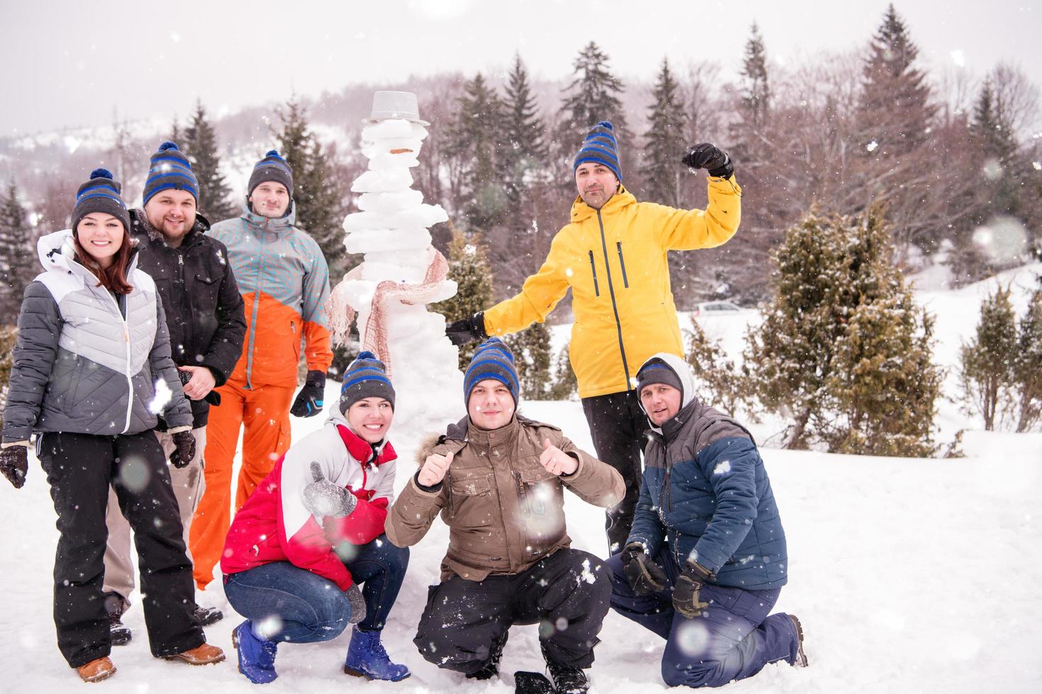 retrato de grupo de jóvenes posando con muñeco de nieve foto