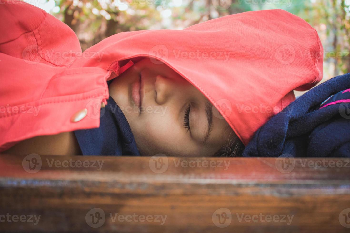 niña pequeña tomando una siesta en un banco del parque. foto