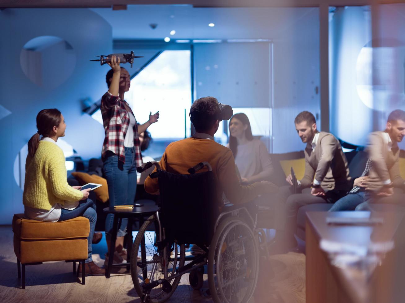 hombre de negocios discapacitado en silla de ruedas en el trabajo en una moderna oficina de trabajo en espacios abiertos con un equipo que utiliza simulación de asistencia de drones de googles de realidad virtual foto