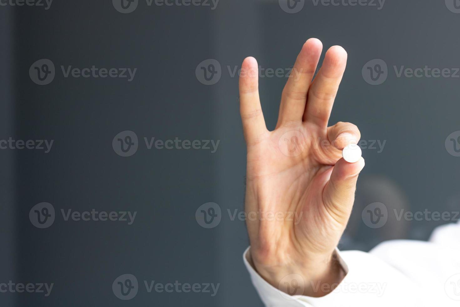 Close-up of man holding a pill. photo