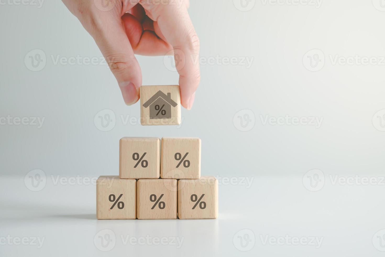 House and property investment and asset management concept. Interest rates, loan mortgage, house tax. Hand holding house with percentage sign on wooden block from wooden block with percent icon. photo