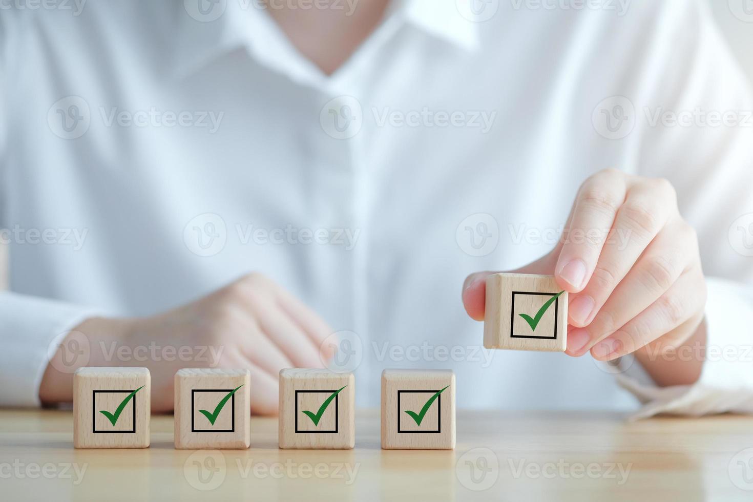 Checklist, Task list, Survey and assessment, Quality Control, Goals achievement and business success. Elections and Voting, Vote, to do list, Hand holding green check mark on wooden block. photo