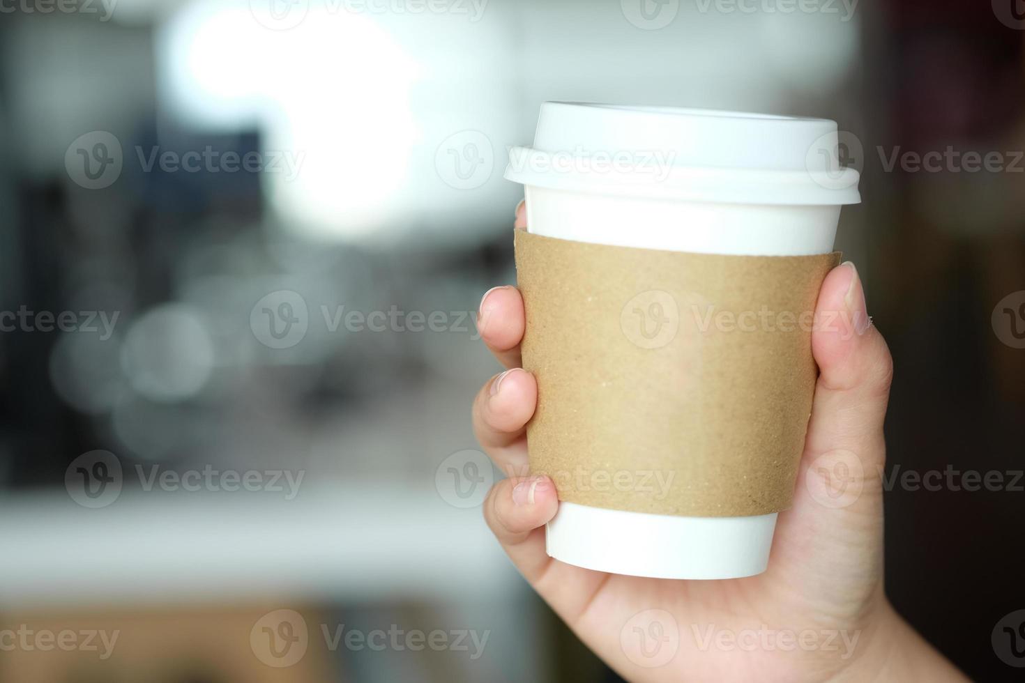 mano de hombre sosteniendo una taza de papel marrón de bebida caliente en la cafetería. Taza de bebida caliente para llevar. foto