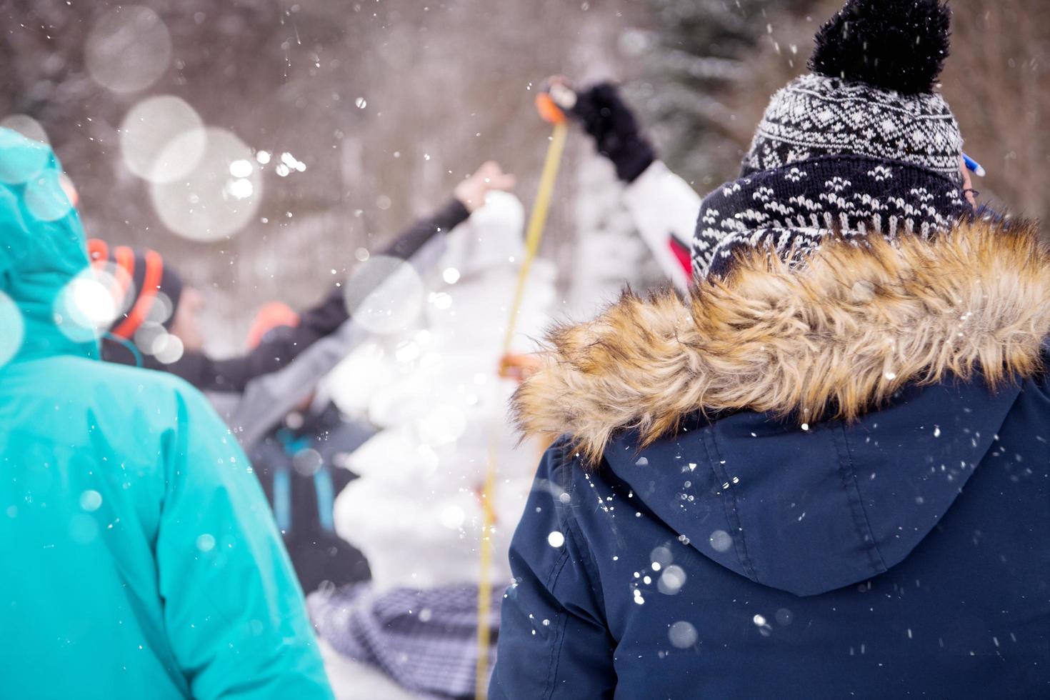 young people measuring the height of finished snowman photo