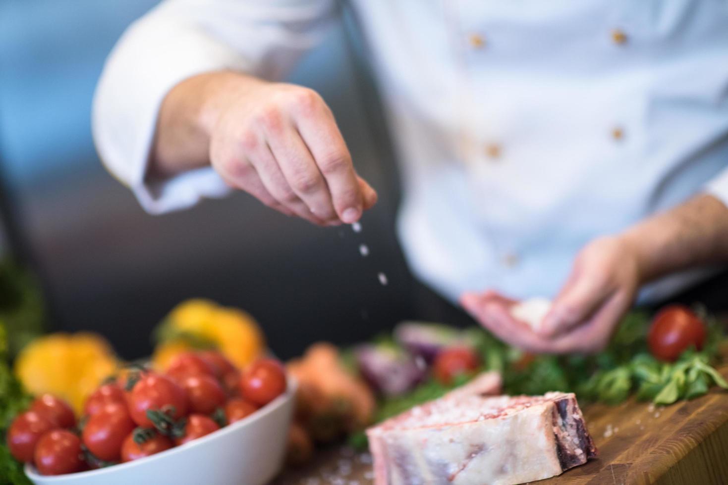 Chef putting salt on juicy slice of raw steak photo