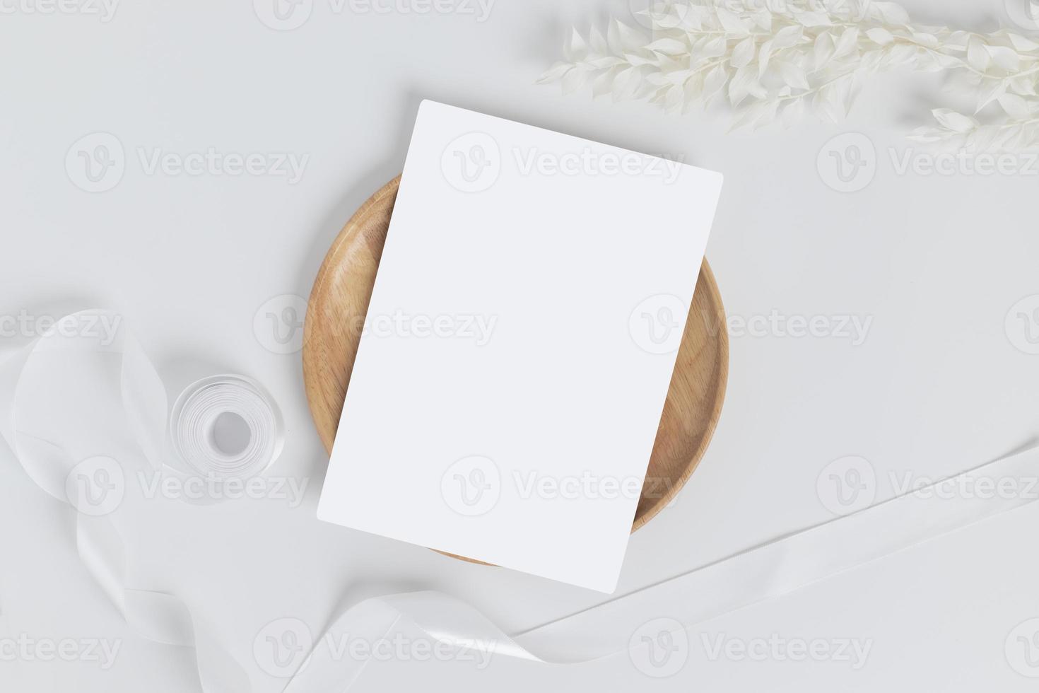 Greeting card or invitation card with white dry flower leaves on wood plate or tray in white background, top view photo