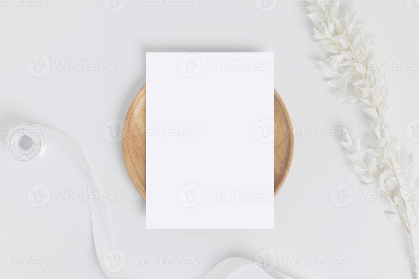 Greeting card or invitation card with white dry flower leaves on wood plate or tray in white background, top view photo