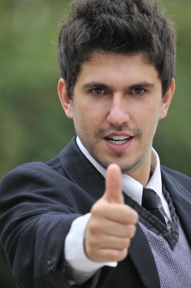 Young caucasian business man in a suite, pointing at camera to y photo