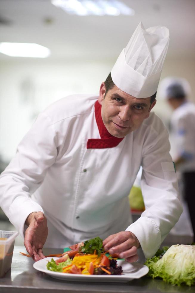 chef en la cocina del hotel preparando y decorando comida foto