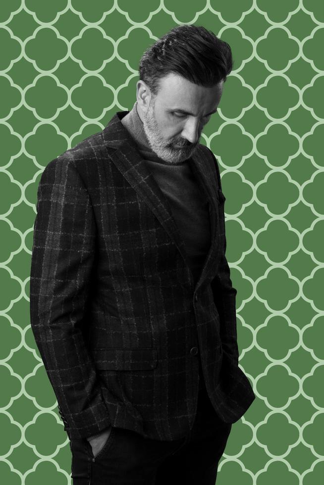 Black and white portrait of a stylish elegant senior businessman with a beard and casual business clothes against retro colorful pattern design background gesturing with hands photo