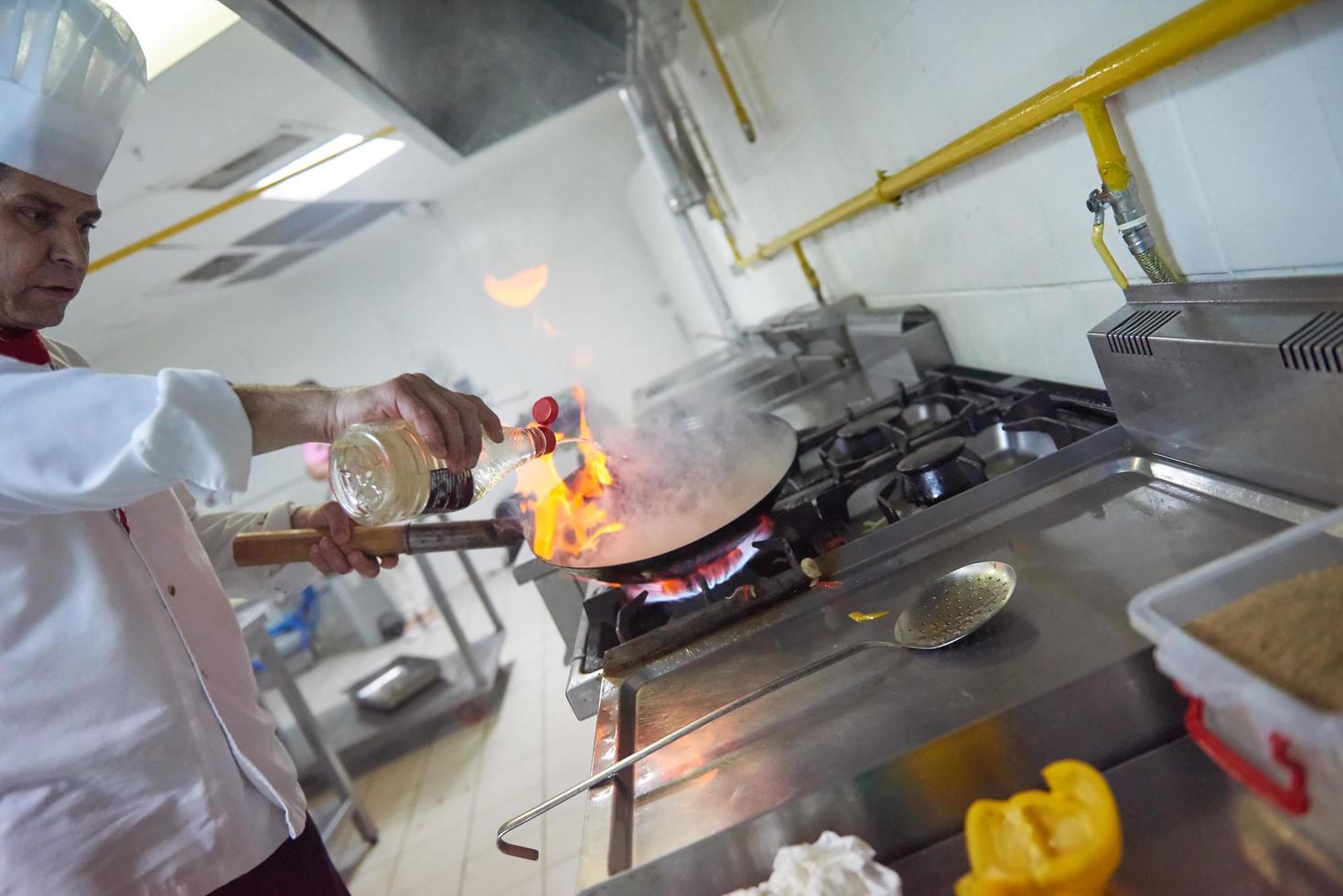 chef in hotel kitchen prepare food with fire photo