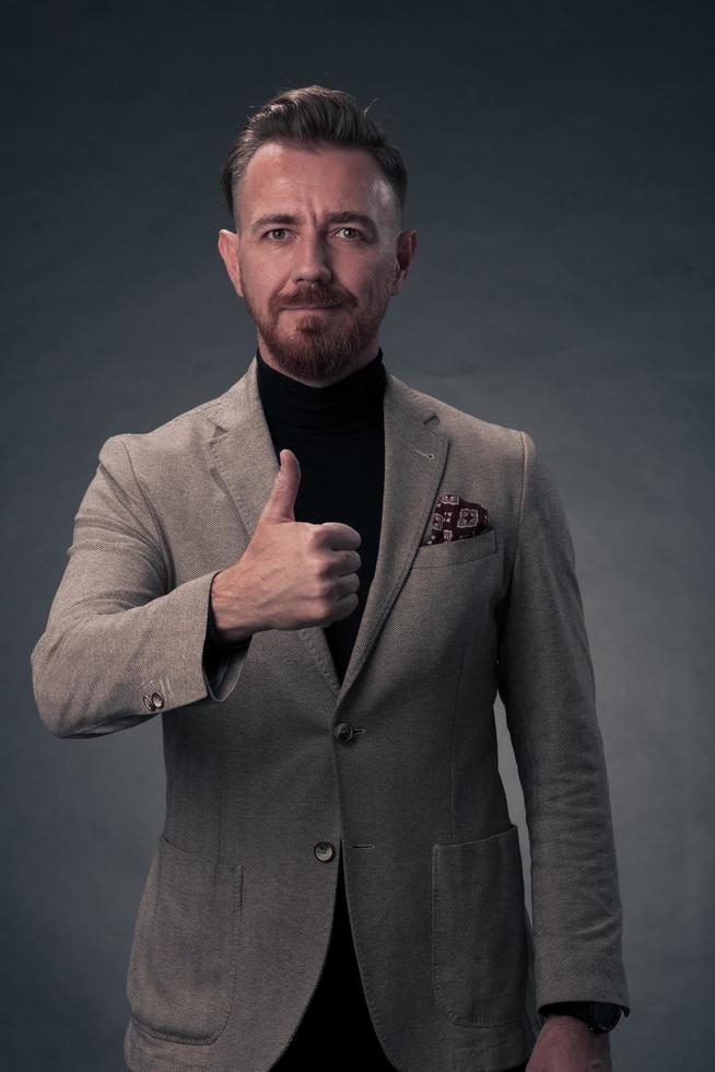 retrato de un elegante hombre de negocios de alto nivel con barba y ropa informal de negocios en un estudio fotográfico aislado en un fondo oscuro gesticulando con las manos foto