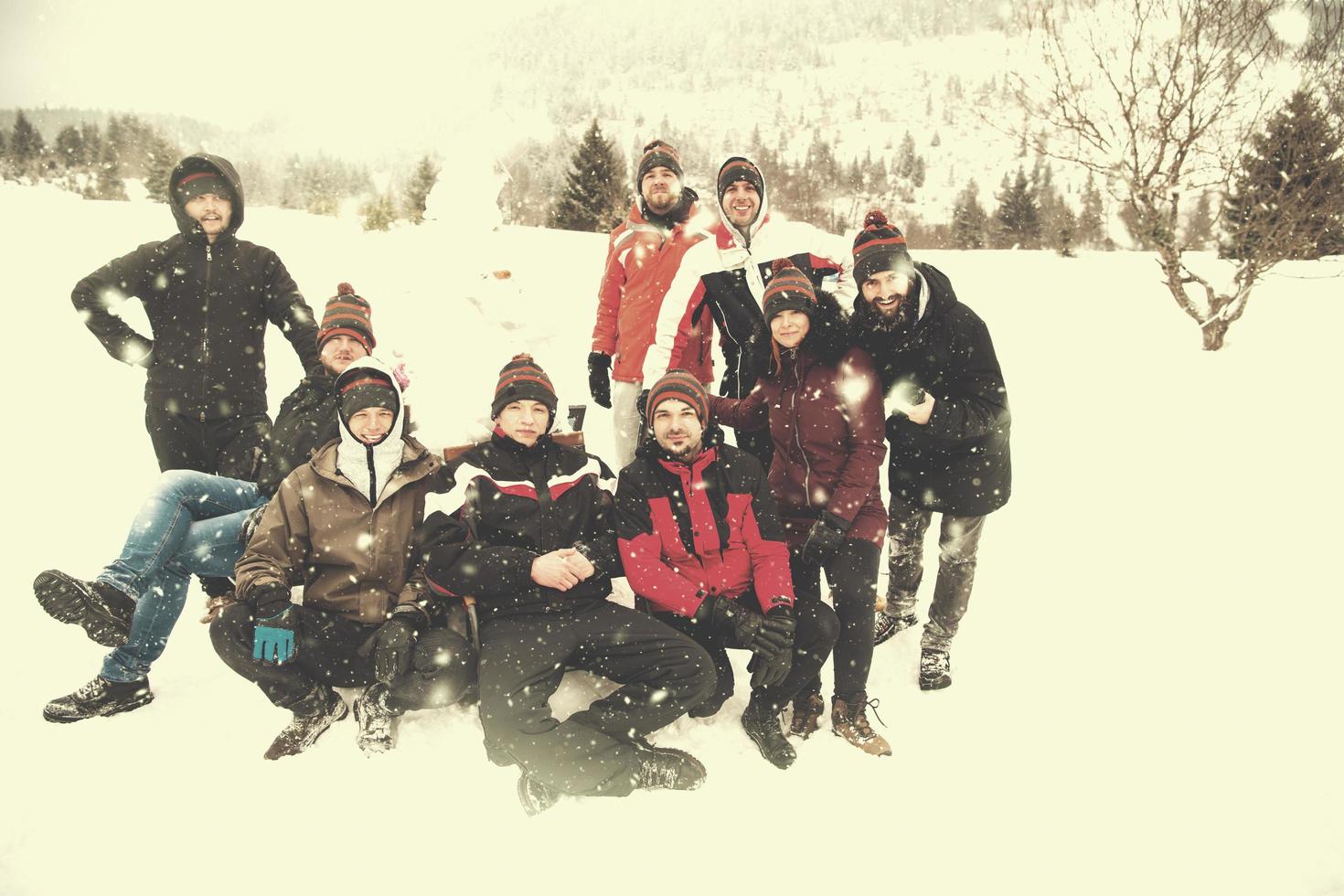 group portait of young people posing with snowman photo