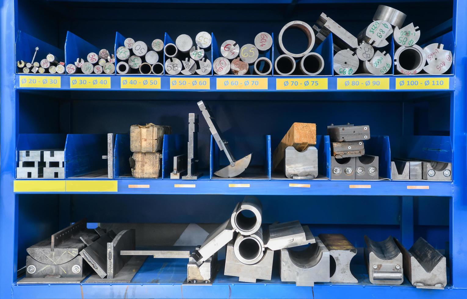 pipes, metal pieces and various metal parts for a CNC machine standing on a shelf photo