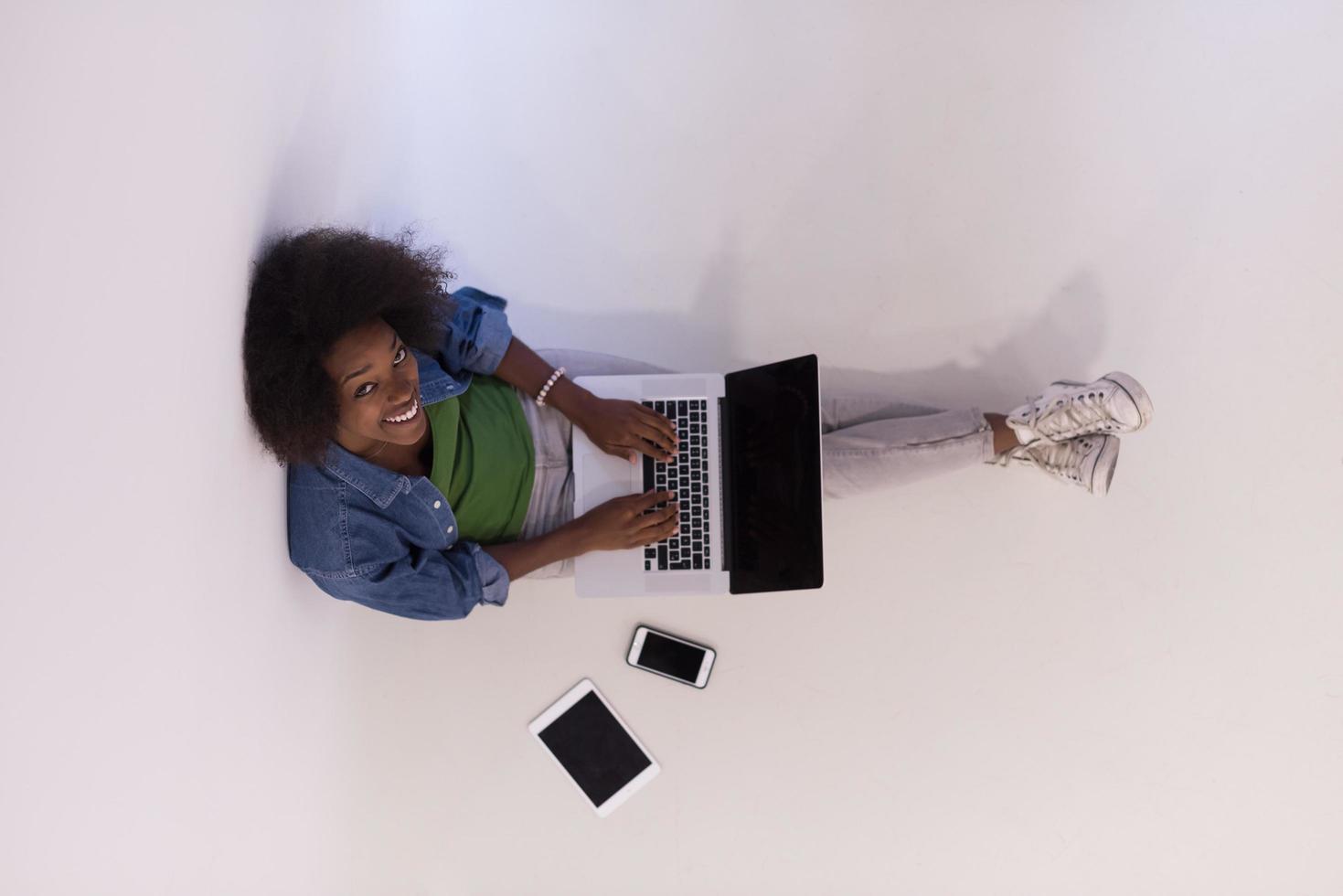 african american woman sitting on floor with laptop top view photo