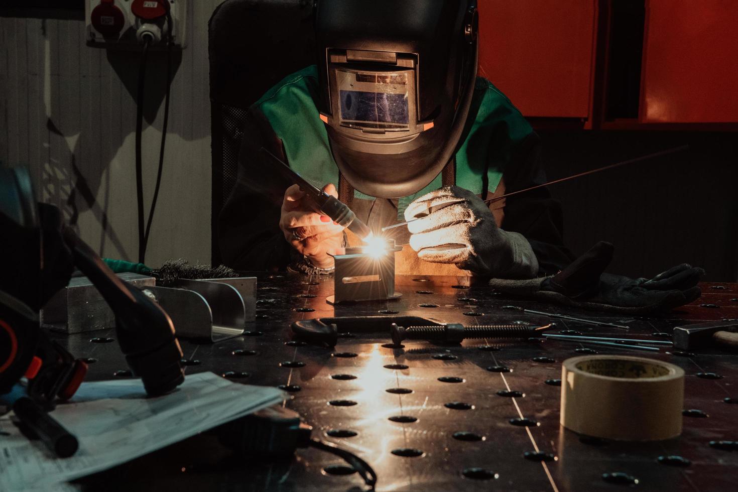 una mujer empleada en una fábrica moderna para la producción y procesamiento de metales en un uniforme de trabajo soldando materiales metálicos foto