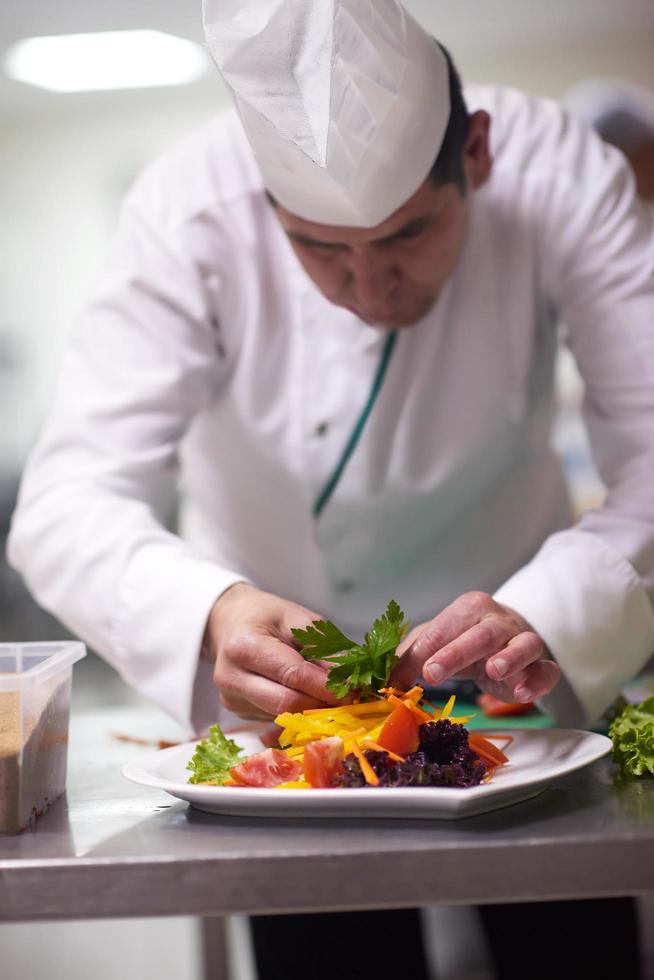 chef in hotel kitchen preparing and decorating food photo