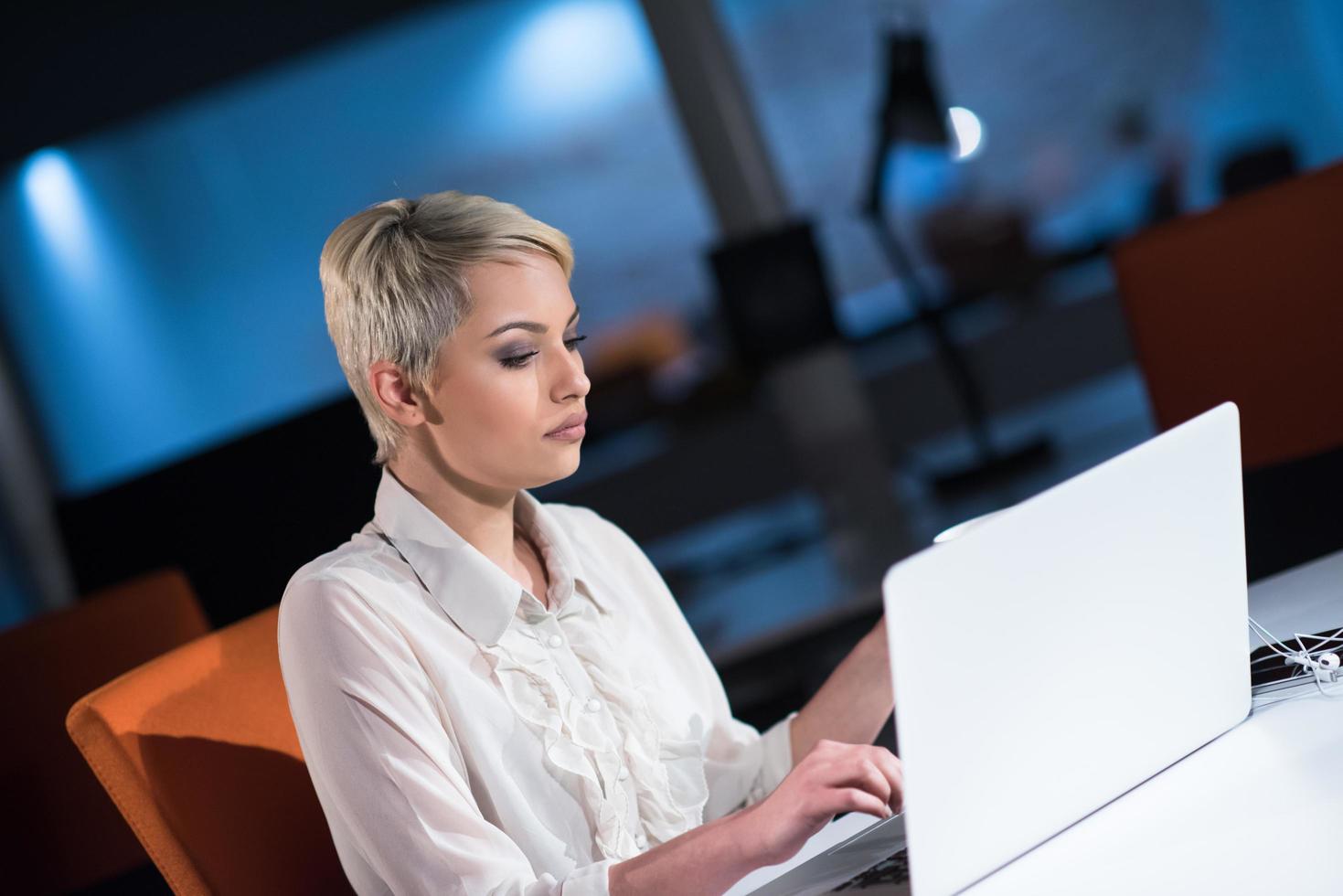 woman working on laptop in night startup office photo